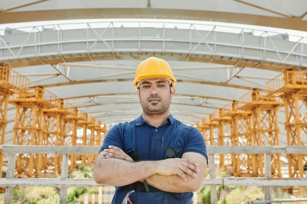 Confident engineer posing with arms crossed on a construction site.