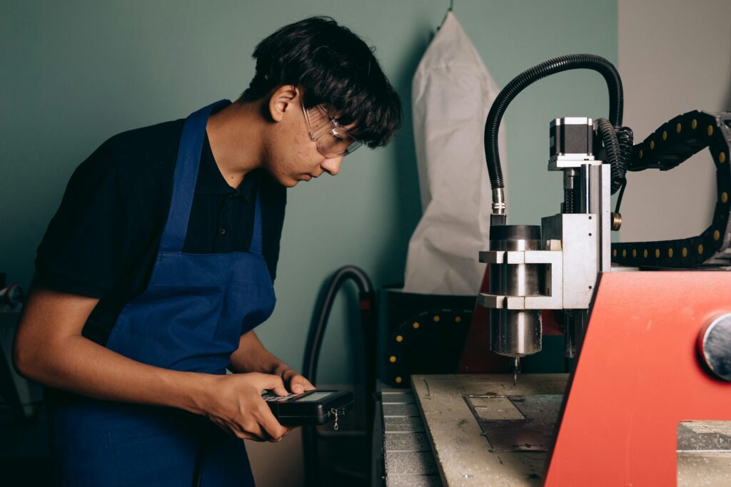 Technician working with CNC machine in an industrial workshop setting, demonstrating concentration and expertise.